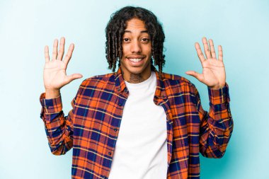 Mavi arka planda izole edilmiş genç Afro-Amerikalı adam on numarayı elleriyle gösteriyor..