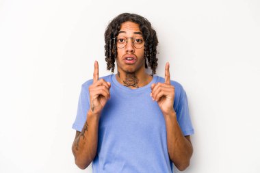 Beyaz arka planda izole edilmiş genç Afro-Amerikalı adam ağzı açık bir şekilde üst tarafı işaret ediyor..