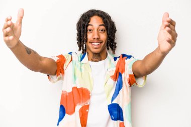 Genç Afrikalı Amerikalı bir adam beyaz arka planda izole edilmiş zaferi ya da başarıyı kutluyor, şaşırmış ve şok olmuş..