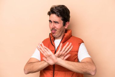 Beyazlı genç bir adam bej arka planda izole edilmiş, inkar jesti yapıyor.