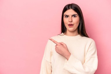 Pembe arka planda izole edilmiş genç beyaz kadın yan tarafı gösteriyor.