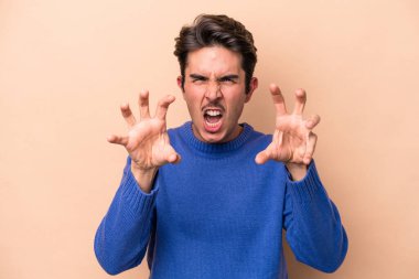 Beyazlı genç bir adam bej arka planda izole edilmiş pençelerini kedi taklidi yaparken gösteriyor, agresif bir hareket..