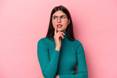 Pembe arka planda izole edilmiş genç beyaz kadın bir strateji planlıyor, bir iş kurmanın yollarını düşünüyor..