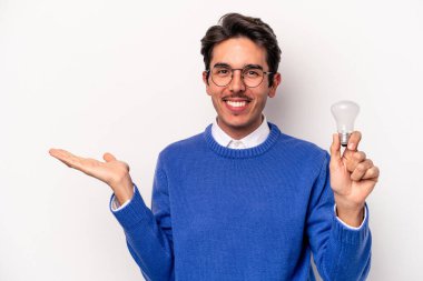 Beyaz arka planda izole edilmiş bir ampul tutan genç beyaz bir adam bir avuç içinde fotokopi alanı ve belinde başka bir el tutuyor..