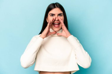 Kafkasyalı genç bir kadın mavi arka planda izole edilmiş. Dedikodu yapıyor, bir şeyleri bildiriyor..