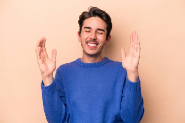 Beyazlı genç bir adam bej arka planda izole edilmiş neşeli bir şekilde gülüyor. Mutluluk kavramı.