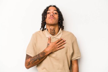 Genç Afrikalı Amerikalı adam beyaz arka planda izole edilmiş bir şekilde yemin ediyor, elini göğsüne koyuyor..