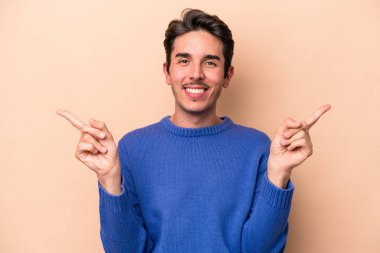 Beyazların arka planında izole edilmiş genç beyaz adam farklı kopya alanlarını gösteriyor, birini seçiyor, parmaklarıyla gösteriyor..