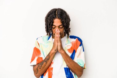 Genç Afrikalı Amerikalı adam beyaz arka planda izole edilmiş dua ediyor, bağlılık gösteriyor, dindar biri ilahi ilham arıyor..