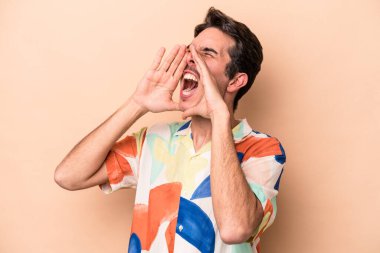 Beyazlı genç adam bej arka planda izole edilmiş ve heyecanlı bir şekilde bağırıyor..