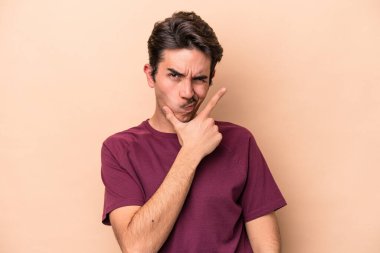 Beyazlı genç bir adam bej arka planda izole edilmiş. Bir strateji planlıyor, bir iş yolu düşünüyor..