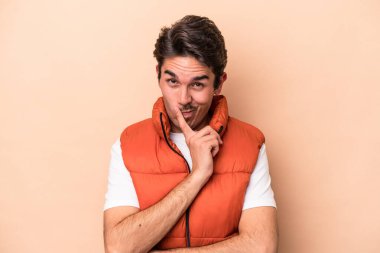 Beyazlı genç bir adam bej arka planda izole edilmiş. Bir strateji planlıyor, bir iş yolu düşünüyor..