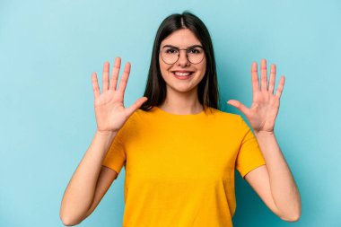 Mavi arka planda izole edilmiş genç beyaz kadın on numarayı elleriyle gösteriyor..
