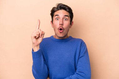 Beyazlı genç bir adam bej arka planda izole edilmiş. Harika bir fikri var, yaratıcılık kavramı..