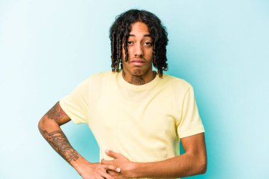 Genç Afrikalı Amerikalı bir adam mavi arka planda karaciğer ağrısı ve mide ağrısı çekiyor..