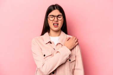 Pembe arka planda izole edilmiş, omuz ağrısı olan beyaz bir kadın..