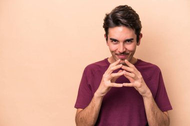 Kafkasyalı genç bir adam, bej arka planda izole edilmiş bir plan kuruyor, bir fikir kuruyor..