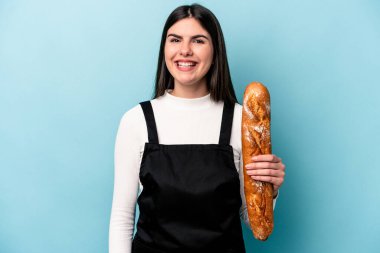 Genç fırıncı Kafkas elinde bir somun ekmekle mavi arka planda izole edilmiş gülüyor ve eğleniyor..