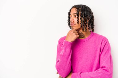 Beyaz arka planda izole edilmiş genç Afrikalı Amerikalı şüpheli ve şüpheci bir ifadeyle yana bakıyor..