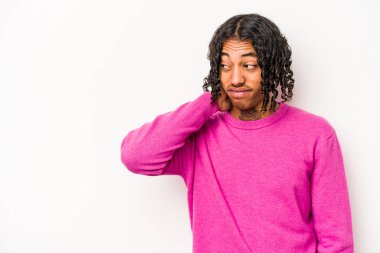 Genç Afrikalı Amerikalı adam beyaz arka planda izole edilmiş kafasının arkasına dokunuyor, düşünüyor ve bir seçim yapıyor..