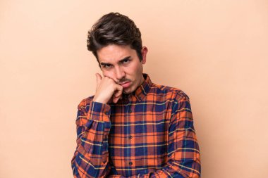 Beyazlı genç adam bej arka planda izole edilmiş. Tekrarlanan bir görevden yorulmuş..