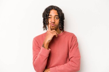 Beyaz arka planda izole edilmiş genç Afrikalı Amerikalı adam alaycı bir ifadeyle kameraya bakıyor..