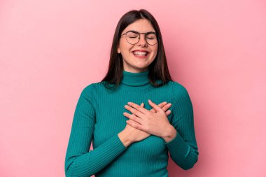 Pembe arka planda soyutlanmış beyaz bir kadın gülüyor, elini yüreğine koyuyor, mutluluk kavramını koruyor..