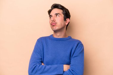 Beyazlı genç adam bej arka planda izole edilmiş. Tekrarlanan bir görevden yorulmuş..