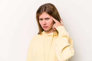 Beyaz arka planda izole edilmiş genç bir Rus kadın şakağı parmağıyla işaret ediyor, düşünüyor ve bir göreve odaklanıyor..