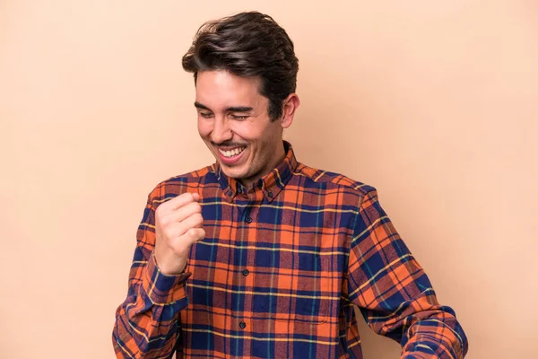 Genç beyaz adam bej arka planda izole edilmiş dans ediyor ve eğleniyor..