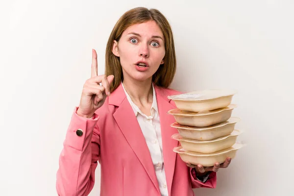 Young business English woman holding tupperware of food isolated on white background having an idea, inspiration concept.