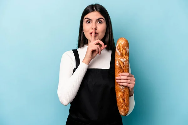 年轻的面包师拿着一块面包 被蓝色背景隔离 保守秘密或要求沉默 — 图库照片