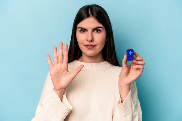 Ung Kaukasisk Kvinna Håller Ett Batteri Isolerad Blå Bakgrund Ler — Stockfoto