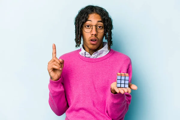 Jovem Afro Americano Segurando Cubo Rubiks Isolado Fundo Azul Tendo — Fotografia de Stock