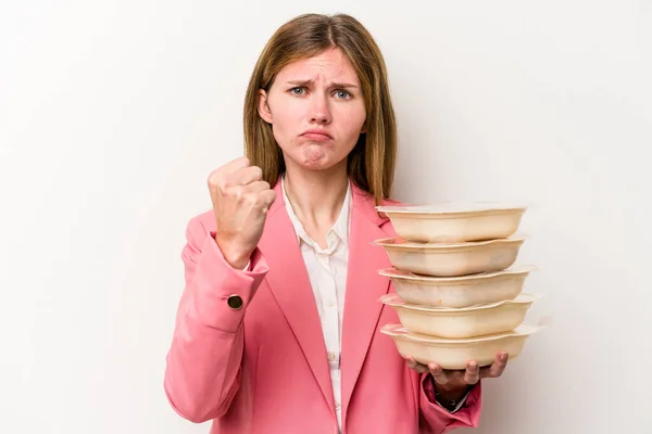 Young business English woman holding tupperware of food isolated on white background showing fist to camera, aggressive facial expression.