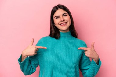 Pembe arka planda izole edilmiş genç beyaz kadın parmaklarıyla aşağıya doğru, olumlu bir his..