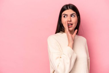 Pembe arka planda izole edilmiş genç beyaz kadın gizli bir sıcak fren haberi veriyor ve yana bakıyor.