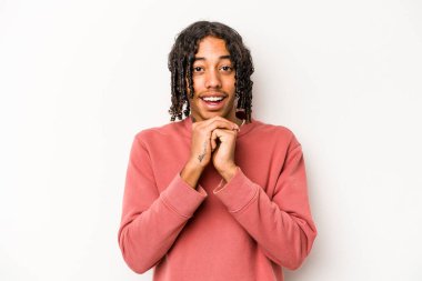 Genç Afro-Amerikalı adam beyaz arka planda izole edilmiş şans için dua ediyor, şaşırmış ve ağzını açıyor..