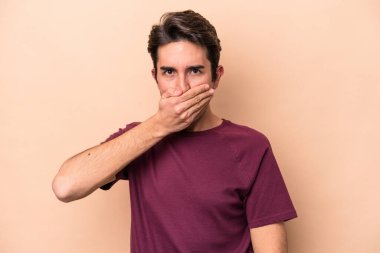 Beyazlı genç bir adam bej arka planda izole edilmiş ağzı kapalı ve elleri endişeli görünüyor..