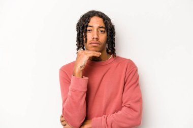 Genç Afrikalı Amerikalı adam beyaz arka planda izole edilmiş şüpheli, belirsiz, seni inceliyor..