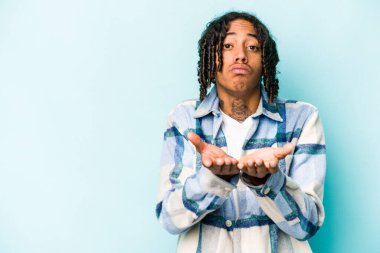 Genç Afrikalı Amerikalı adam mavi arka planda izole edilmiş dudaklarını kıvırıyor ve hava öpücüğü göndermek için avuç içi tutuyor..