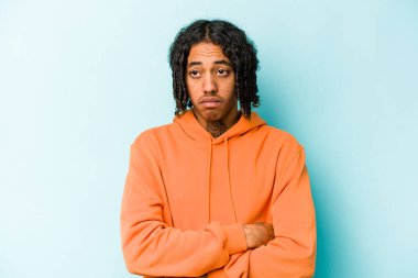 Genç Afrikalı Amerikalı adam mavi arka planda izole edilmiş. Tekrarlanan bir görevden yorulmuş..