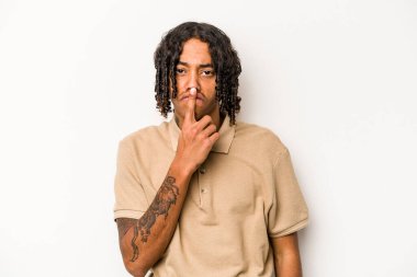 Genç Afrikalı Amerikalı bir adam beyaz arka planda izole edilmiş düşünüyor, yukarı bakıyor, yansıtıyor, düşünüyor, bir fantezi kuruyor..