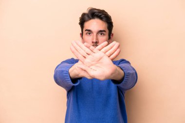 Beyazlı genç bir adam bej arka planda izole edilmiş, inkar jesti yapıyor.