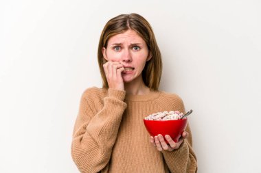 Beyaz arka planda izole edilmiş mısır gevreği yiyen genç bir İngiliz kadın tırnak yiyor, gergin ve çok endişeli..