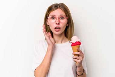 Beyaz arka planda izole edilmiş dondurma tutan genç İngiliz kadın şaşırdı ve şok oldu..