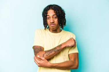 Genç Afrikalı Amerikalı adam mavi arka planda izole edilmiş dirsek masajı yapıyor, kötü bir hareketin ardından acı çekiyor..