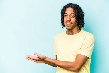 Genç Afro-Amerikalı bir adam mavi arka planda izole edilmiş. Elinde bir fotokopi alanı var..