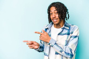 Mavi arka planda izole edilmiş genç Afro-Amerikalı adam işaret parmağıyla fotokopi alanını işaret ederek şok oldu..