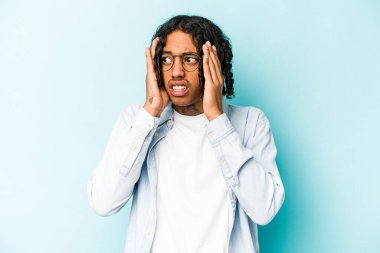 Genç Afrikalı Amerikalı adam mavi arka planda izole edilmiş korkmuş ve korkmuş..